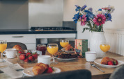 Mesa de desayuno con zumo de naranja, croissants y flores en una tiny house Valleichalet, Ackersate, Países Bajos.