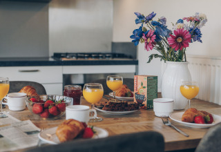 Breakfast table with orange juice, croissants, strawberries and flowers in Valleichalet, Ackersate, Netherlands.