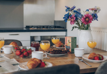 Colazione con succo d’arancia, croissant e fiori nella tiny house Valleichalet, Ackersate, Paesi Bassi.