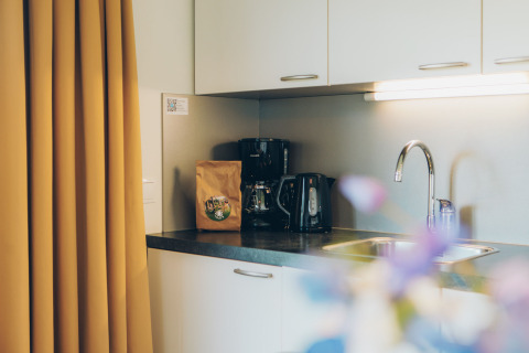 Compact kitchen area at the Valleichalet tiny house in Ackersate Holiday Park, Netherlands, with coffee maker.