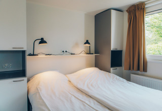 Bedroom at the Valleichalet tiny house in Holiday park Ackersate, Netherlands, with twin beds and modern decor.