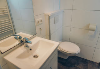 Modernes, kompaktes Badezimmer mit Waschbecken, Spiegel und Wandtoilette im Valleichalet, Niederlande.