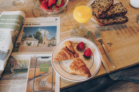 Breakfast with croissants, strawberries, orange juice, and newspaper at Valleichalet, Holiday park Ackersate, Netherlands.