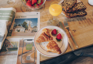 Breakfast with croissants, strawberries, orange juice, and newspaper at Valleichalet, Holiday park Ackersate, Netherlands.