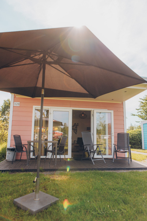 Outdoor area of the Valleichalet tiny house at Holiday park Ackersate, Netherlands, featuring patio and furniture.