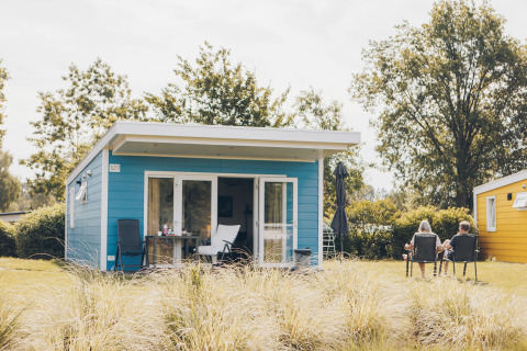 To personer slapper af foran et blåt tiny house Valleichalet i ferieparken Ackersate, Holland.
