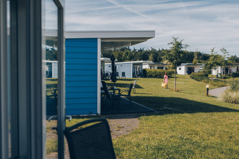 Uitzicht op tiny houses bij Valleichalet in Holiday park Ackersate, Nederland, met grasvelden en wandelende gast.