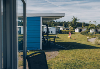 View of small houses at Valleichalet in Holiday Park Ackersate, Netherlands, with lawns and a visitor walking.