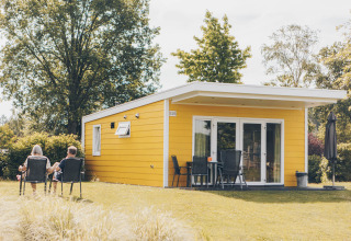 To personer slapper af udenfor en gul Valleichalet tiny house på Holiday park Ackersate, Holland.