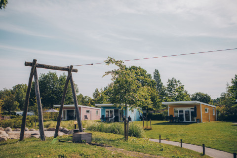 Valleichalet Tiny Houses im Holiday Park Ackersate, Niederlande, mit Grünflächen und Bäumen.