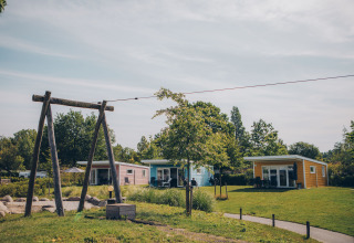 Valleichalet tiny houses at Holiday park Ackersate in the Netherlands, surrounded by green lawns and trees.