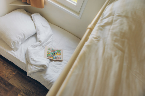 Cozy sleeping area in the Valleichalet tiny house with a book on bed at Holiday park Ackersate, Netherlands.