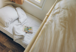 Gemütliches Schlafbereich im Valleichalet Tiny House mit Buch auf dem Bett im Ferienpark Ackersate, Niederlande.