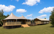 Safari tent Glamfield Lodge Deluxe met hot tub en houten terras in een ruim, groen landschap.