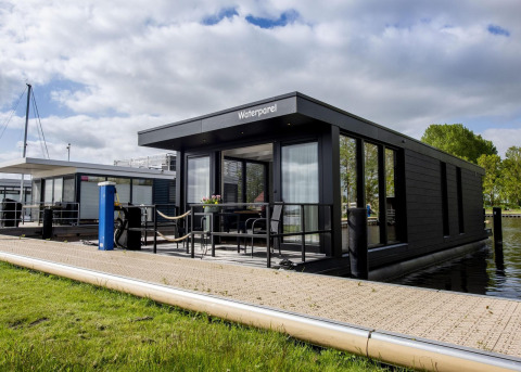 Casa flotante moderna 'De Waterparel' en Welcome In - Friesland, Países Bajos, atracada junto al muelle.