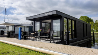 Casa flotante moderna 'De Waterparel' en Welcome In - Friesland, Países Bajos, atracada junto al muelle.
