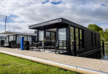 Casa flotante moderna 'De Waterparel' en Welcome In - Friesland, Países Bajos, atracada junto al muelle.
