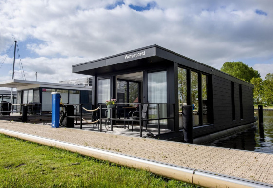 Casa flotante moderna 'De Waterparel' en Welcome In - Friesland, Países Bajos, atracada junto al muelle.