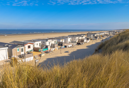 Vista di casette sulla spiaggia e dune sabbiose in un parco vacanze con alloggi glamping sul mare.
