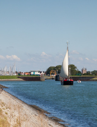 Senda ciclista y velero en un canal cerca de Koudekerke-Dishoek, Zelanda, Países Bajos, bajo cielo despejado.