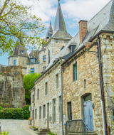 Steinbauten mit Türmen in einem Ferienpark mit Glamping-Angebot unter blauem Himmel und Wolken.