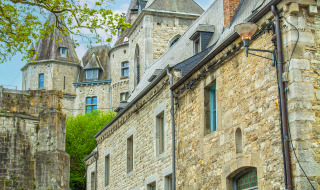 Edificios de piedra y torreones en un parque vacacional con opciones de glamping bajo un cielo azul.