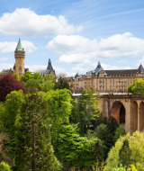 Puente y edificio histórico rodeados de árboles verdes bajo un cielo azul cerca de Wallendorf-pont, Luxemburgo.