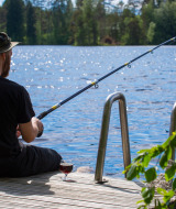 Man sits fishing on a pier