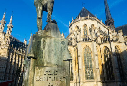 Estatua con un libro y fuente ante una iglesia histórica en el centro de Molenstede, Brabante Flamenco.