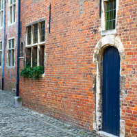 Calle adoquinada con antiguas casas de ladrillo y puertas arqueadas en Molenstede, Brabante Flamenco, Bélgica.