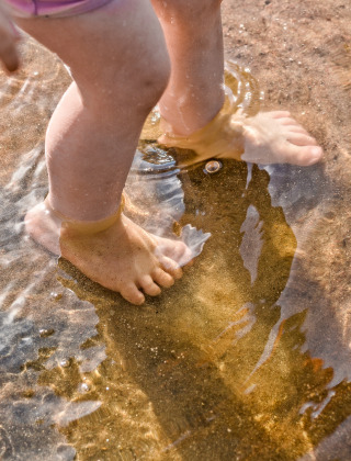 Kinderfüße im Wasser eines Sees