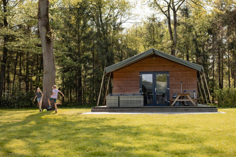 Dos niños juegan al fútbol frente a una tienda Safarilodge en Camping the Noetselerberg en los Países Bajos.