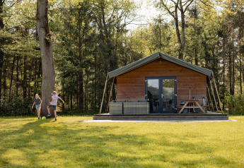 Twee kinderen spelen voetbal voor een safarilodge tent op Camping de Noetselerberg in Nederland.