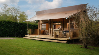 Tienda safari 'the bartender' con instalaciones sanitarias en Holiday Park Mölke, Países Bajos, rodeado de césped.