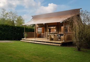 Safaritent 'the bartender' met eigen sanitair bij Vakantiepark Mölke in Nederland, omgeven door gras en natuur.