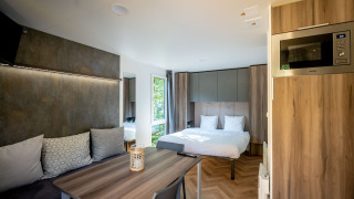 Casa tiny Lodge moderna en Urban-Gardens, Bélgica, con cama, zona de estar, mesa de comedor y microondas.