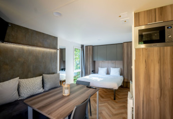 Casa tiny Lodge moderna en Urban-Gardens, Bélgica, con cama, zona de estar, mesa de comedor y microondas.