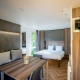 Moderne Lodge tiny house ved Urban-Gardens i Belgien, med seng, siddeområde, spisebord og mikrobølgeovn.