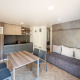 Moderne lodge på Urban-Gardens i Belgien med tekøkken, spisebord, sofa og lys indretning.