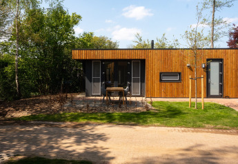 Vooraanzicht van Happy Oak Lodge in Holiday Park Mölke, Nederland, met een strakke houten gevel.