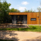 Facade af Happy Oak Lodge i Holiday Park Mölke, Nederlandene, omgivet af grønt og moderne trædesign.