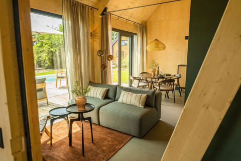 Interior moderno de lodge con sofá, comedor y grandes ventanales en Unbrick One, Brinckerduyn, Países Bajos.
