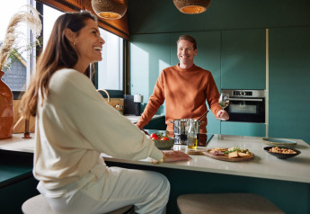 Dos personas disfrutan de un momento relajado en la moderna cocina de Unbrick One | Sauna and Pool en Brinckerduyn, Países Bajos.