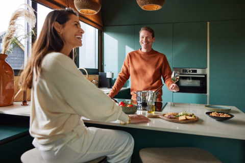Twee personen genieten samen in de moderne keuken van Unbrick One | Sauna and Pool bij Brinckerduyn, Nederland.