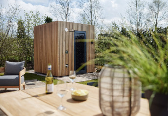 Sauna moderna de madera y terraza en Brinckerduyn, Unbrick One, con vino y sillas, Países Bajos.