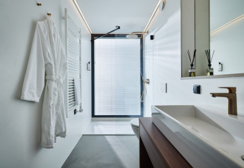 Bagno moderno bianco con accappatoio, lavabo e doccia a Unbrick One | Sauna and Pool, Brinckerduyn, Paesi Bassi.