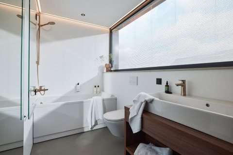 Modern bathroom at Unbrick One with large window, bathtub, shower, wooden accents and sleek design.