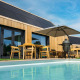 Moderne lodge med træfacade, terrasse, pool, parasol og grill ved Brinckerduyn i Holland under blå himmel.