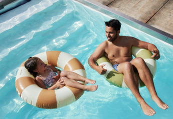 Hombre y niña se relajan en flotadores en la piscina de Unbrick One | Sauna and Pool en Brinckerduyn, Países Bajos.