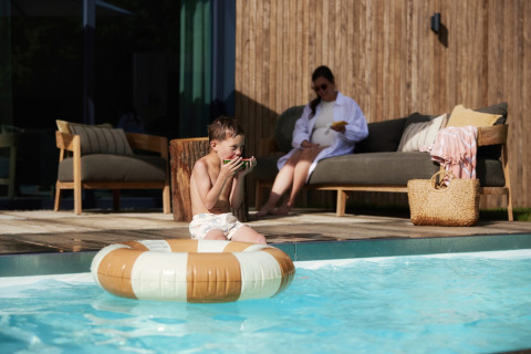 Junge isst Wassermelone am Pool im Unbrick One | Sauna und Pool in Brinckerduyn, Niederlande.